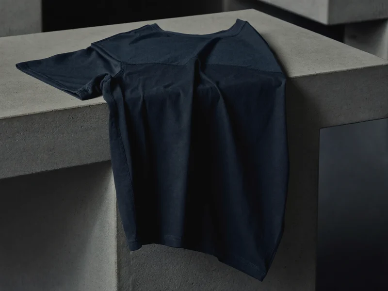 Dunkles technisches Trainingsshirt, gefaltet und drapiert auf einer Betonbank im Gym